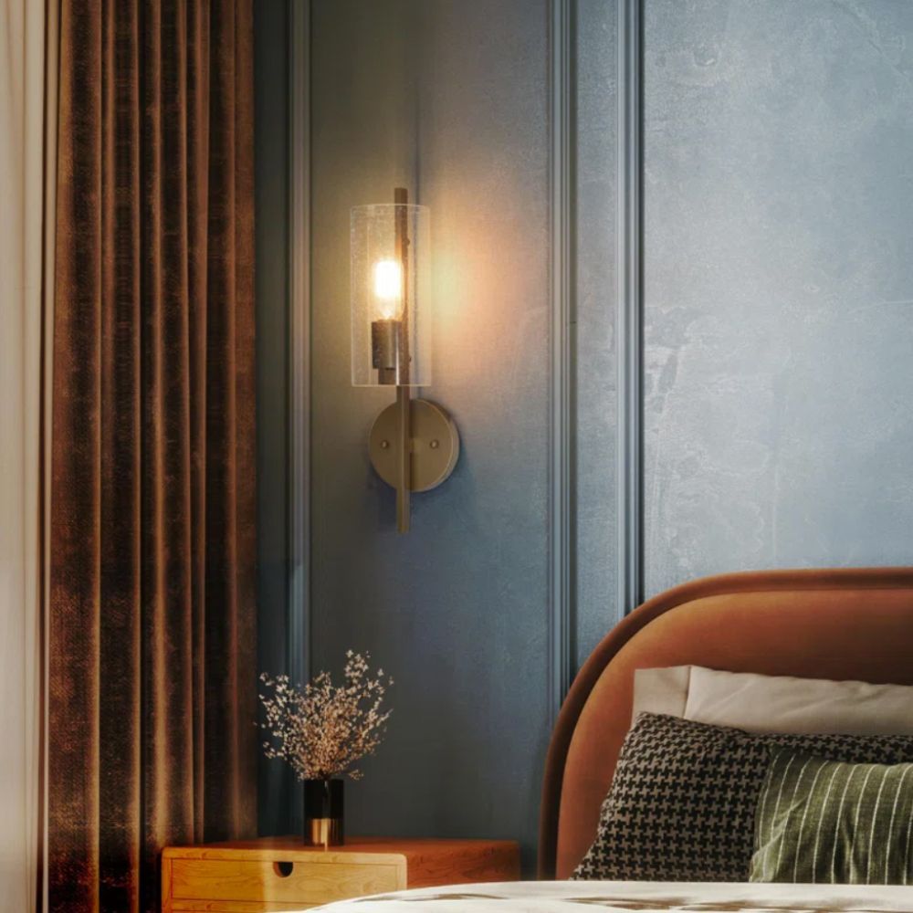 glass and metallic wall light on grey wall with rust coloured bed and curtains and wooden bedside table