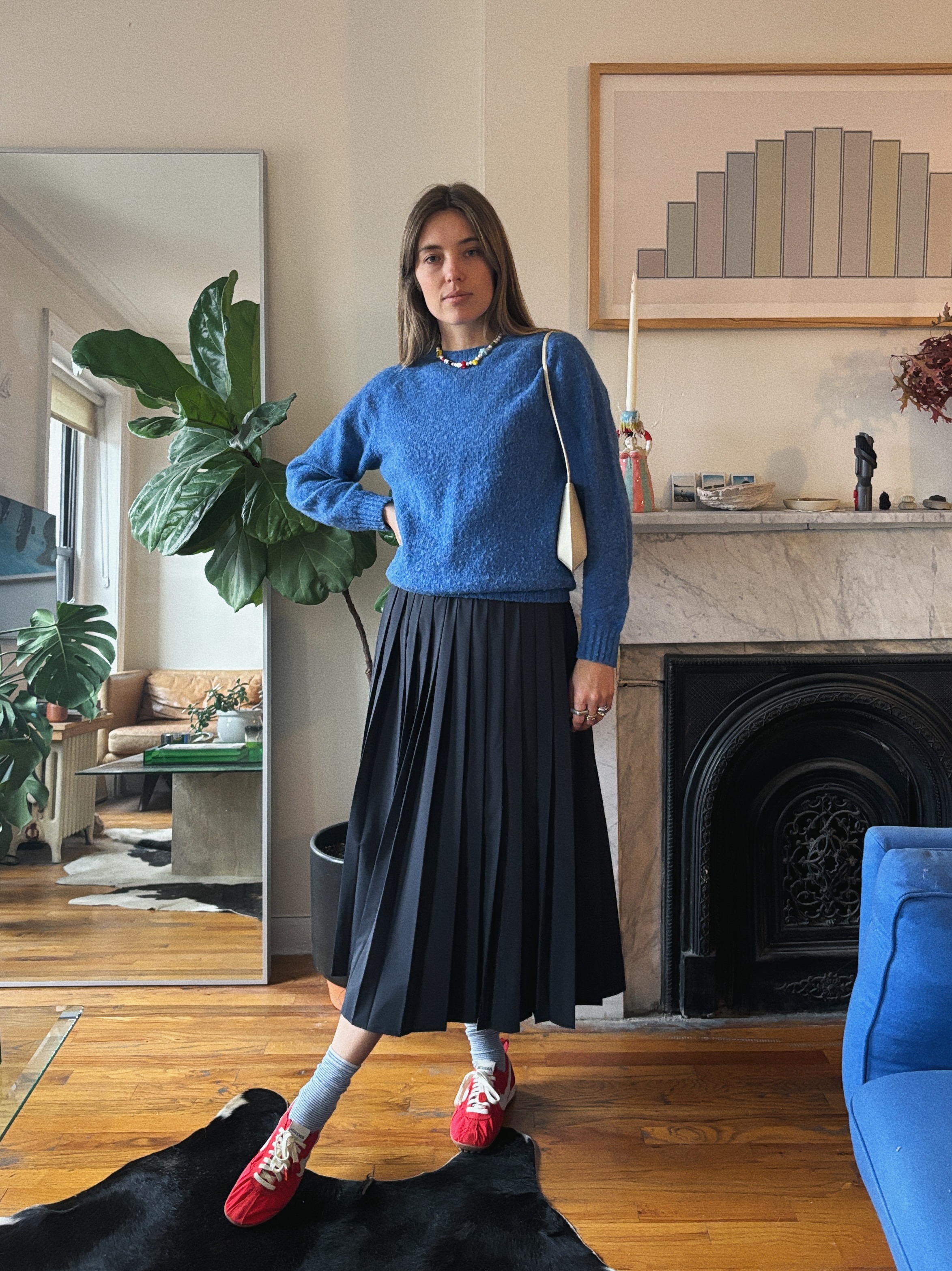 Aemilia Madden wearing a blue sweater, a black skirt, and red shoes