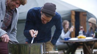 Two men cooking at camp