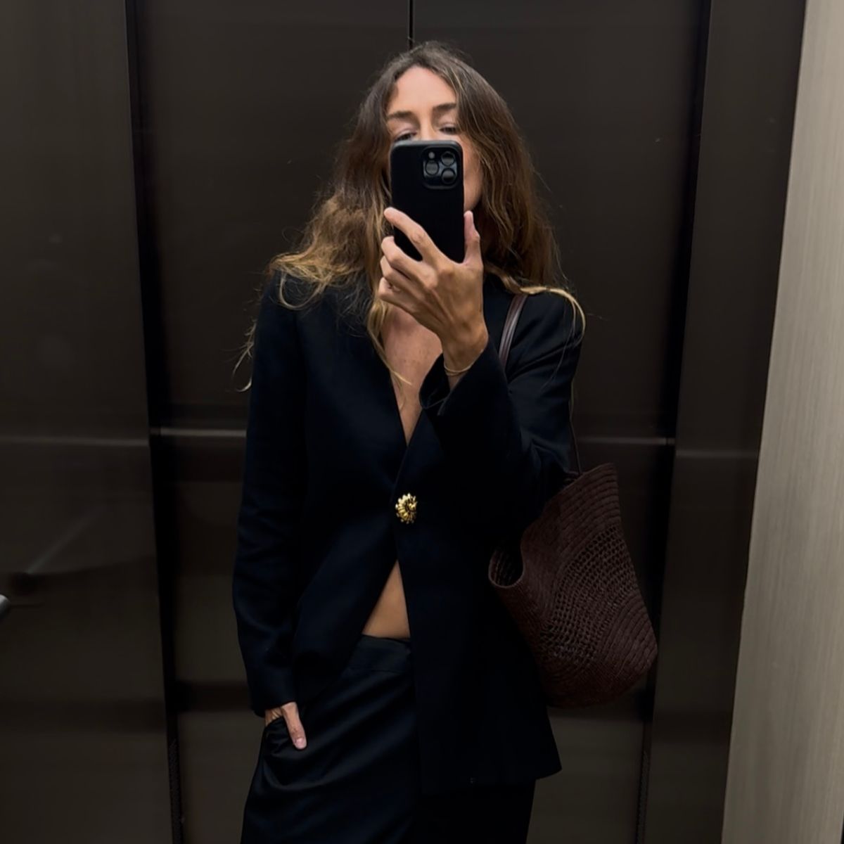 Angie wears a grey t-shirt, cream jumper, blue jeans