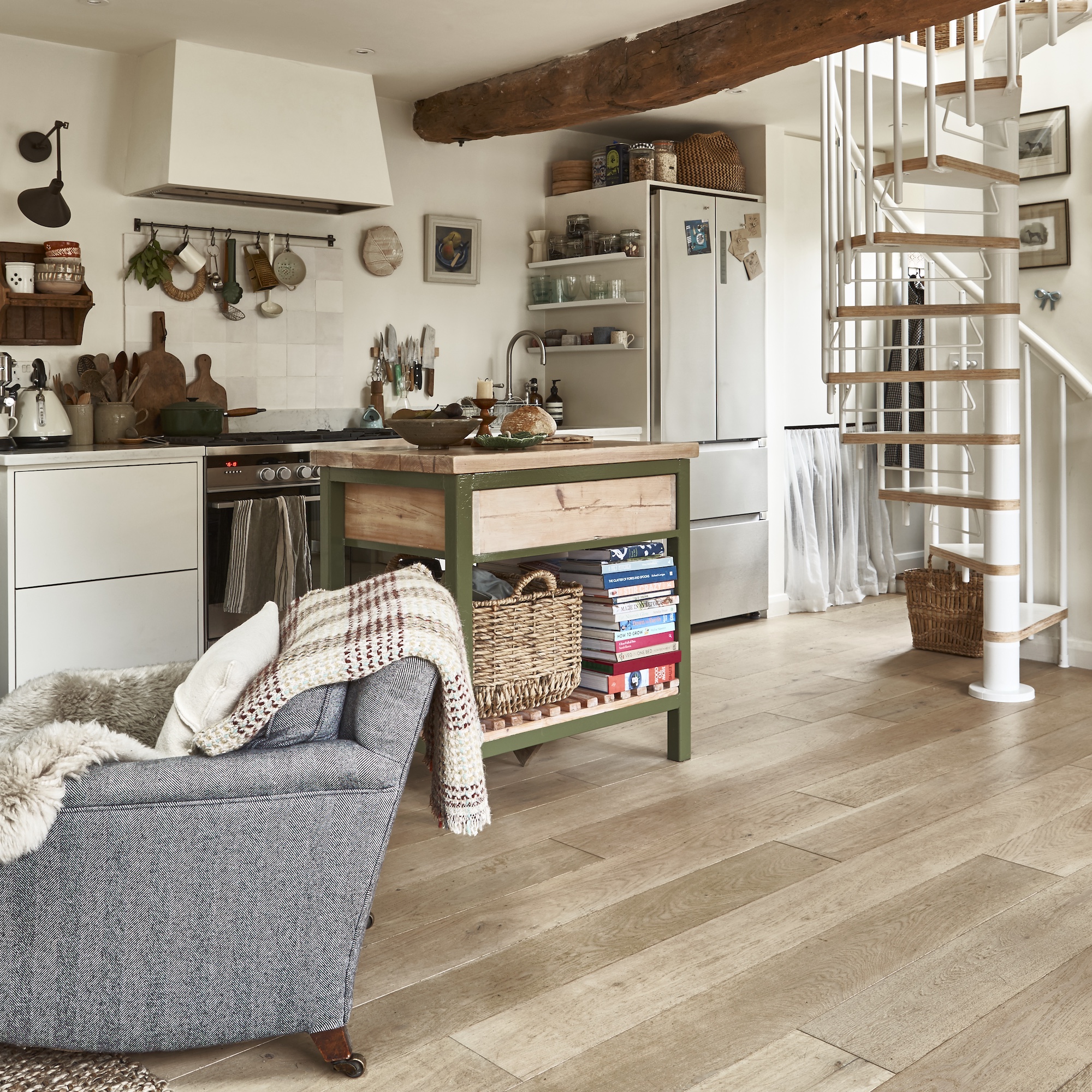 galley kitchen with small island with green metal frame and spiral staircase
