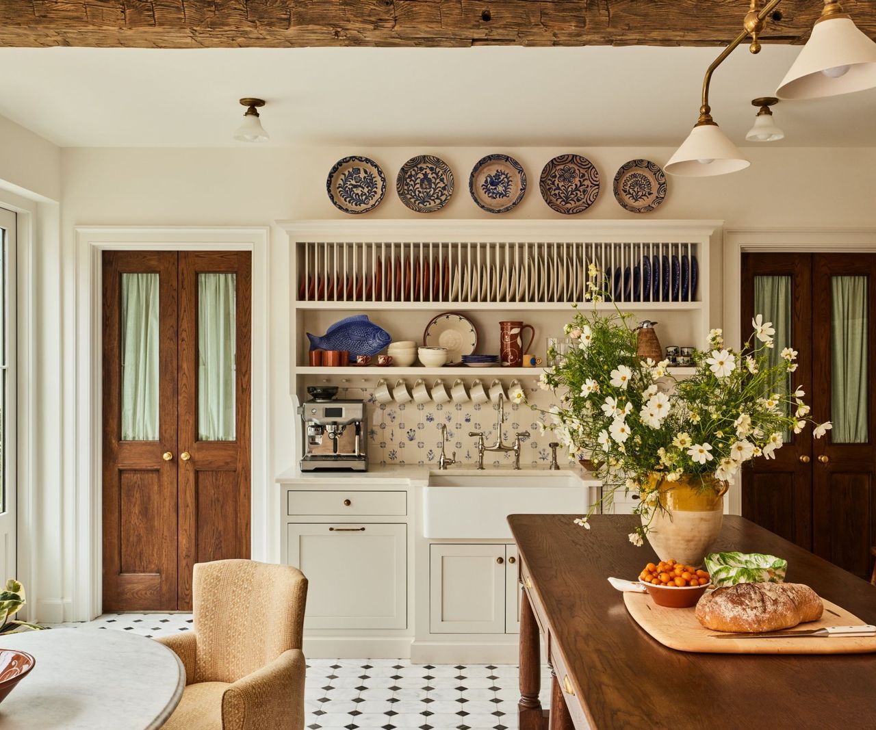 Bistro style kitchen with open dresser, black and white tiled floor, pendant lighting, beams and plates on wall