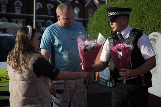 A police officer receives flowers to lay at the scene of a multiple stabbing attack on July 29, 2024 in Southport, England.