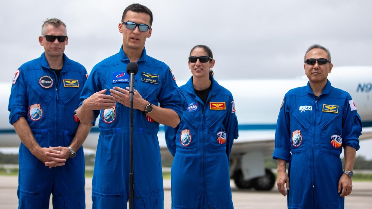 Top Stories Tamfitronics four astronauts in a row with flight suits on. one of them speaks at a microphone while three stand in the background. all are wearing sunglasses