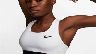 Woman in a white Nike sports crop top. Nike tick logo is black