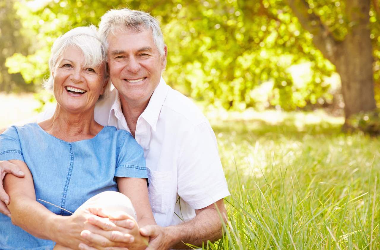 Senior couple sitting on grass together relaxing