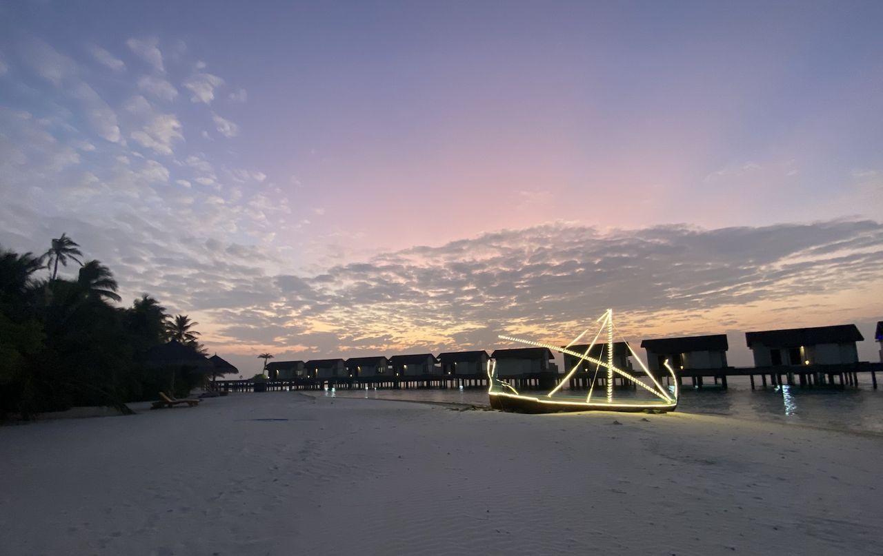 Over water villas photographed from the beach at sunset at Atmosphere Kanifushi in the Maldives