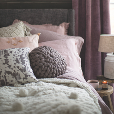 Double bed with grey and pink bedding and cushions.