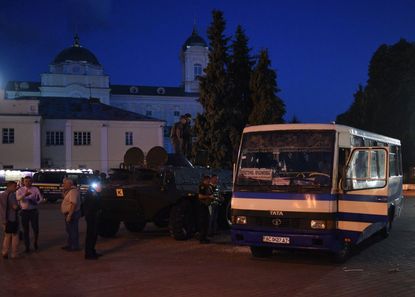 Servicemen and law enforcement officers gather at the scene after police freed all hostages from a bus and arrested the armed man who held them for over 12 hours in the city of Lutsk, some 40