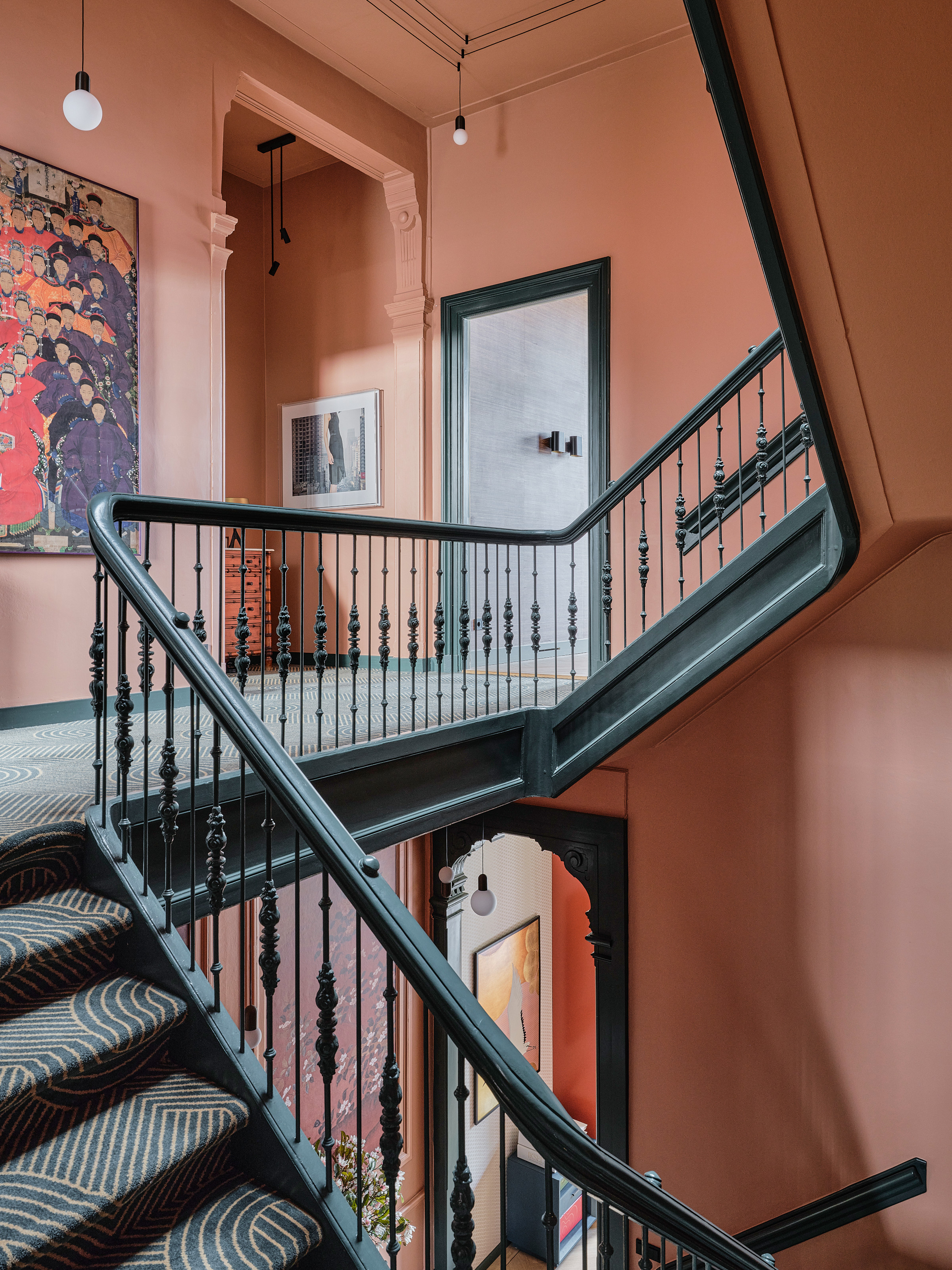 Pink hallway and landing with dark green painted period staircase
