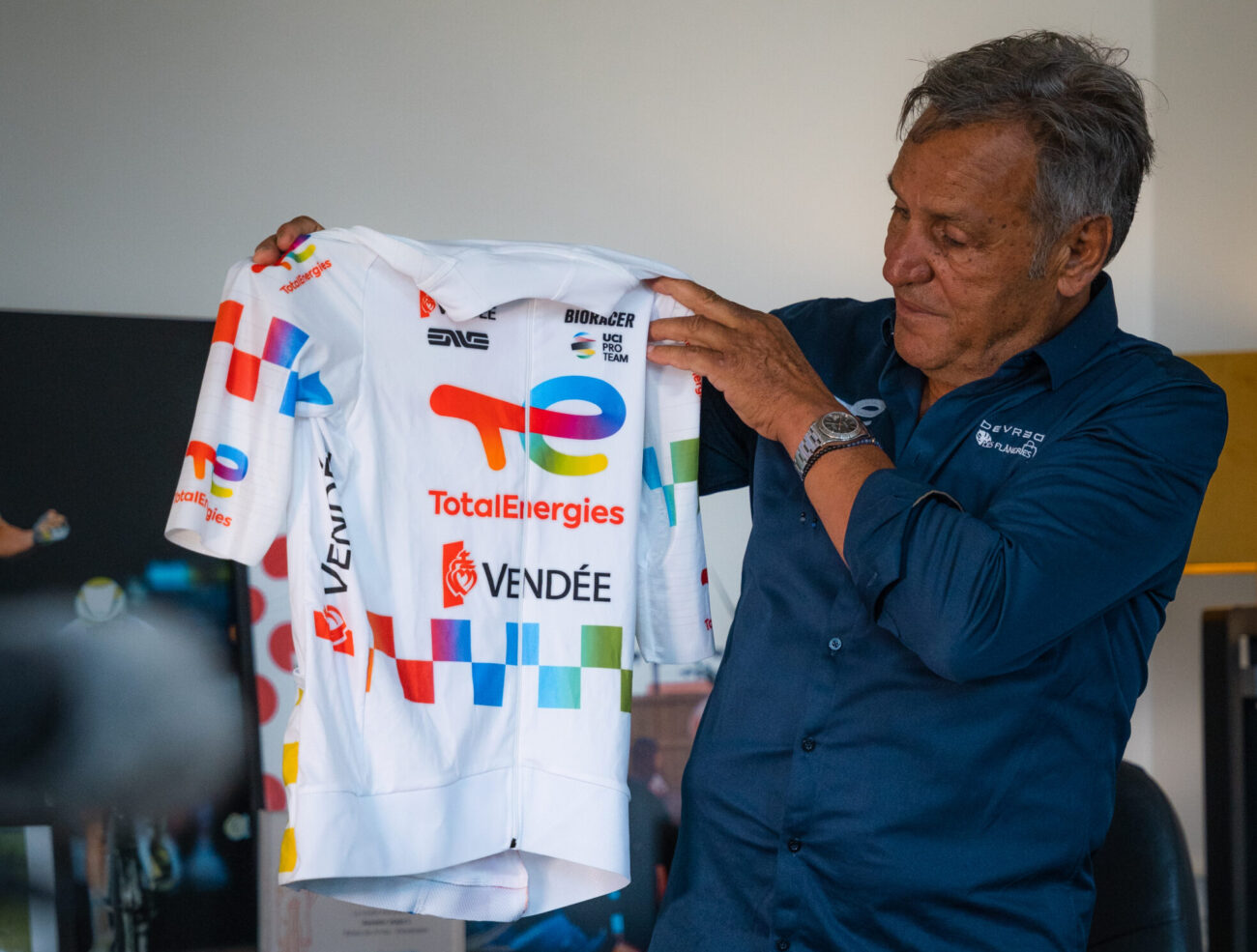 Jean-René Bernaudeau holding the new TotalEnergies jersey for the Tour de France
