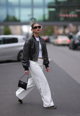 woman wearing white top, white jeans, and leather jacket