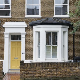 brick house with yellow door and glass window