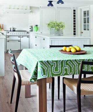 white kitchen with white Shaker style cabinets and dining table with green patterned tablecloth