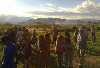 People gather near the smoking remains of the helicopter crash in Argentina.
