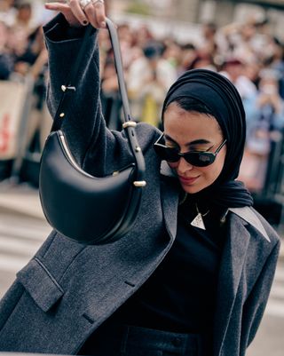 A woman carrying a black bag at Fashion Month street style.