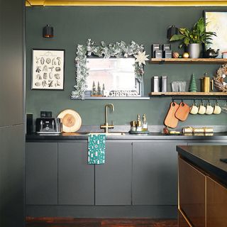 Black kitchen cabinets with sink and gold tap and wooden shelves