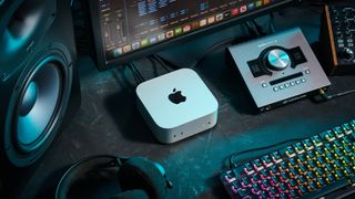 An Apple Mac Mini M4 on a desk with an audio interface, studio monitors, and studio headphones