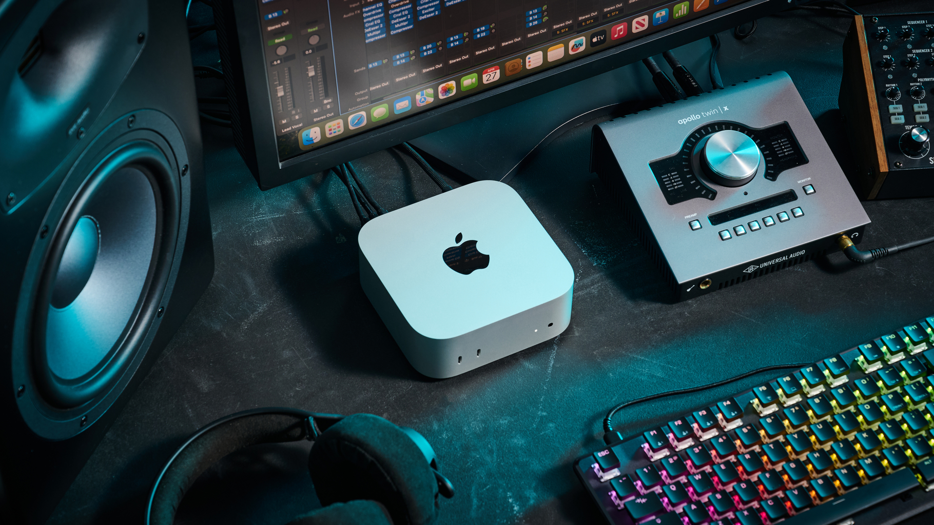 An Apple Mac Mini M4 on a desk with an audio interface, studio monitors, and studio headphones