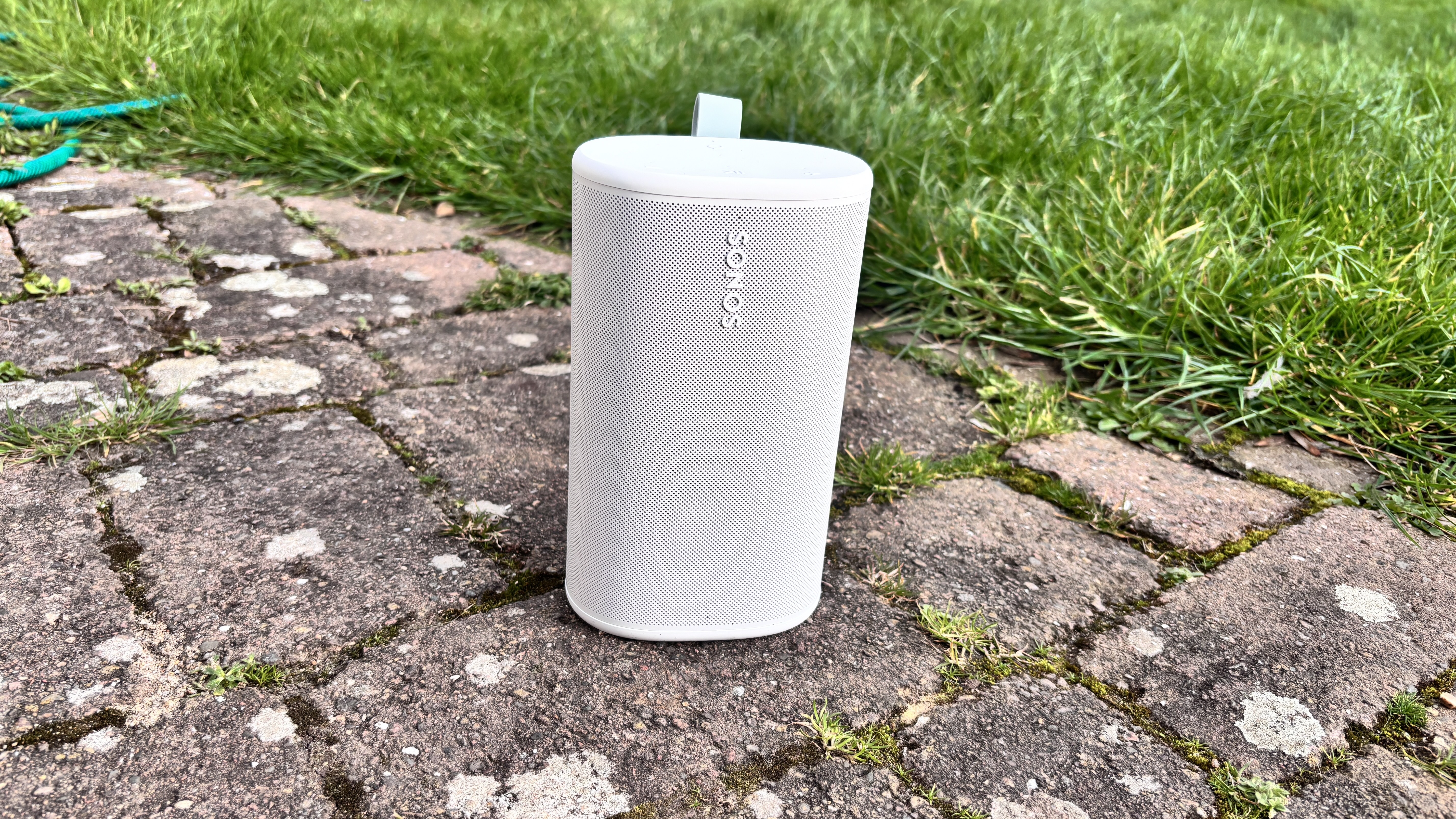 White Sonos Play wireless speaker on a patio next to some grass