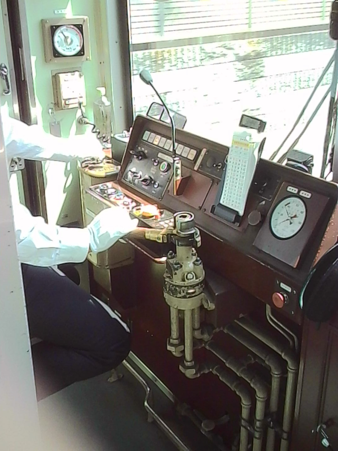 Driver&amp;rsquo;s cab of a Japanese train with control panels, gauges, and levers.