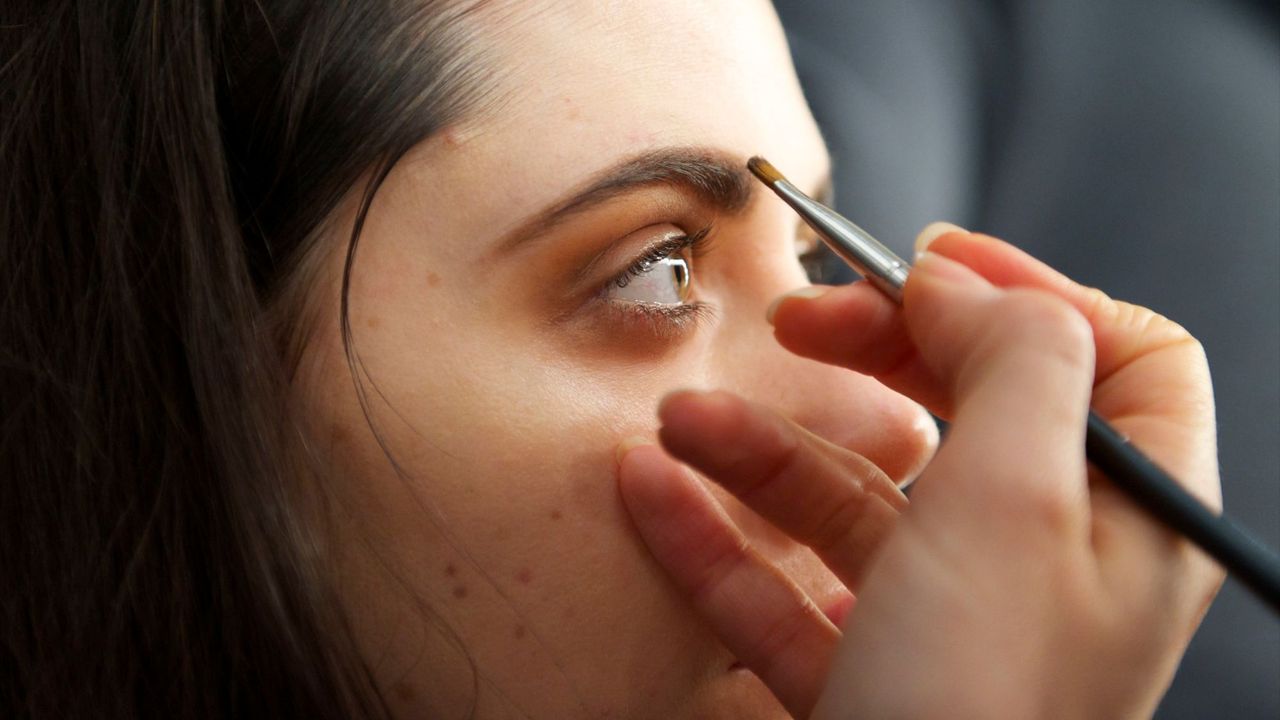 Make-up artist applying brow powder on model