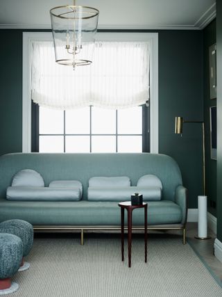Living room with dark blue-green walls and turquoise sofa