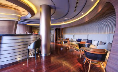 Curved bar featuring hardwood floor and leather and wood seating.