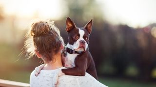 Woman carrying dog over her shoulder