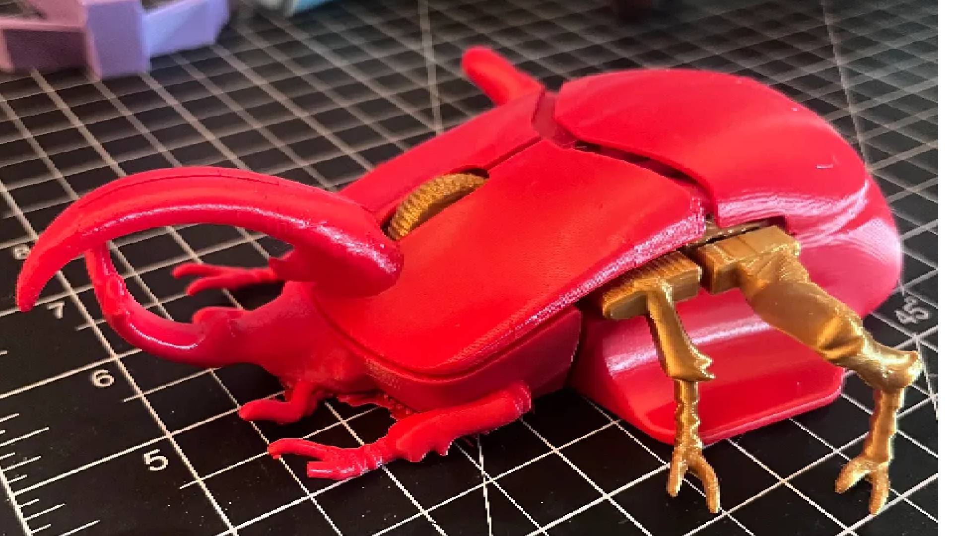 Red customized Pulsefire Saga Pro mouse with beetle design.