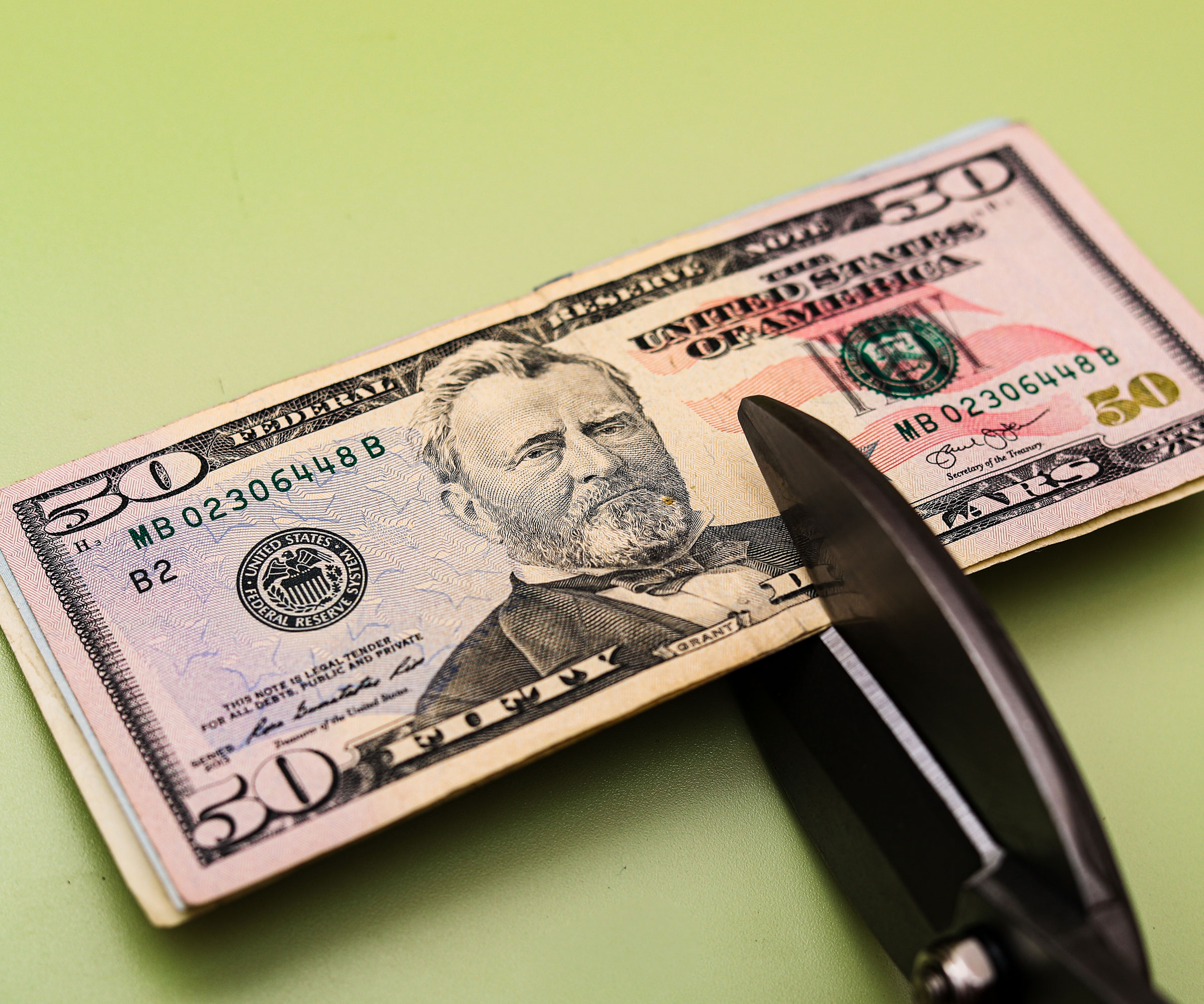 cutting 50 dollar bills with black pruning shears