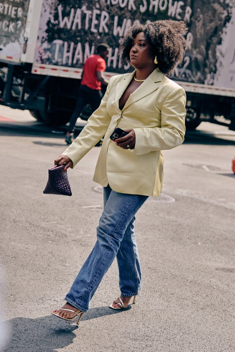a woman at new york fashion week wearing a yellow blazer and blue straight-leg jeans