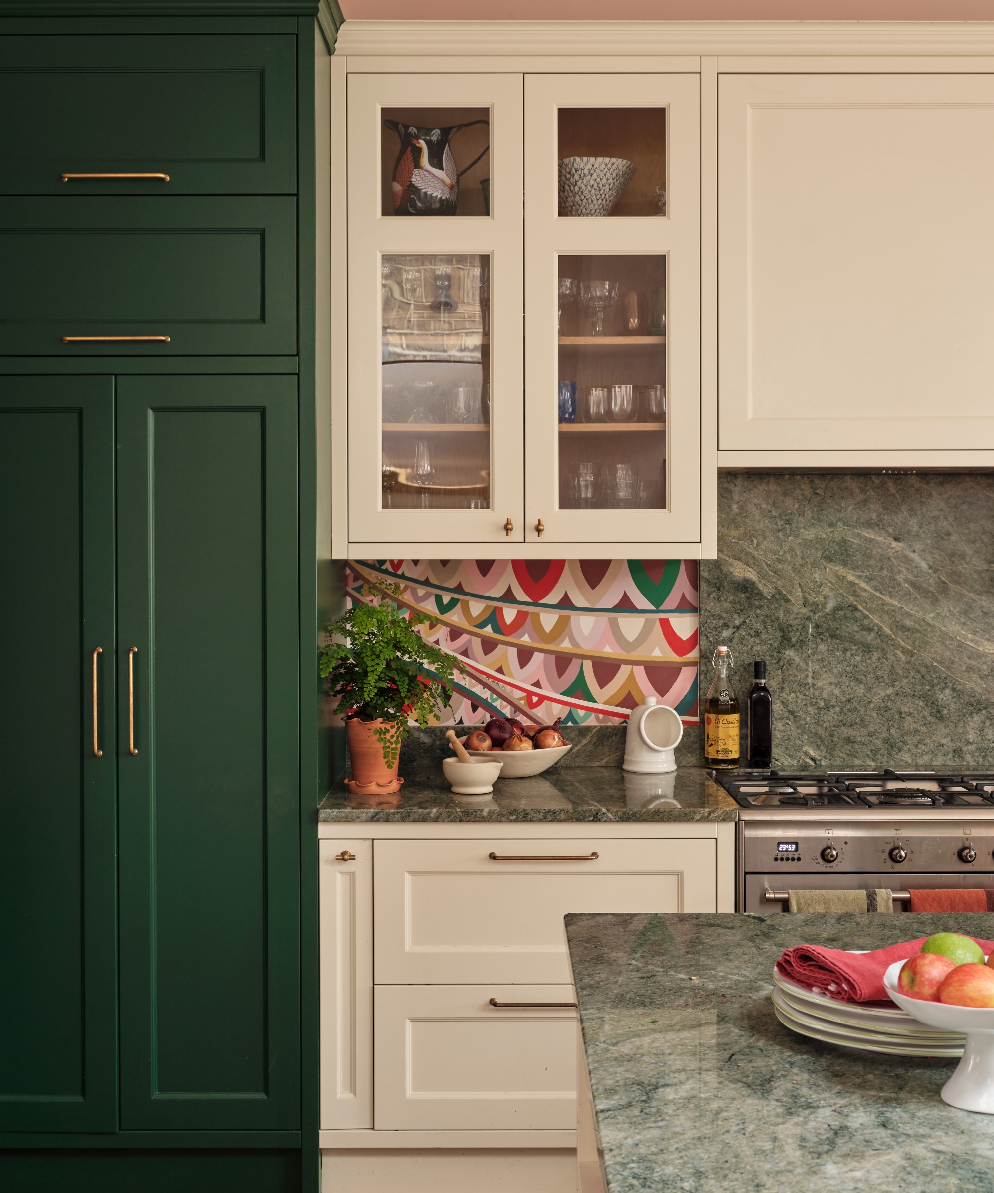 A kitchen with white cabinets flanking a stainless steel range, green full length cabinets, and green granite countertops