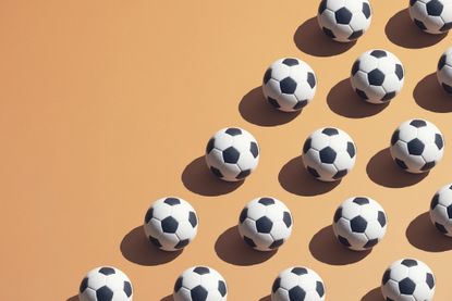 Footballs arranged in lines on an orange backdrop