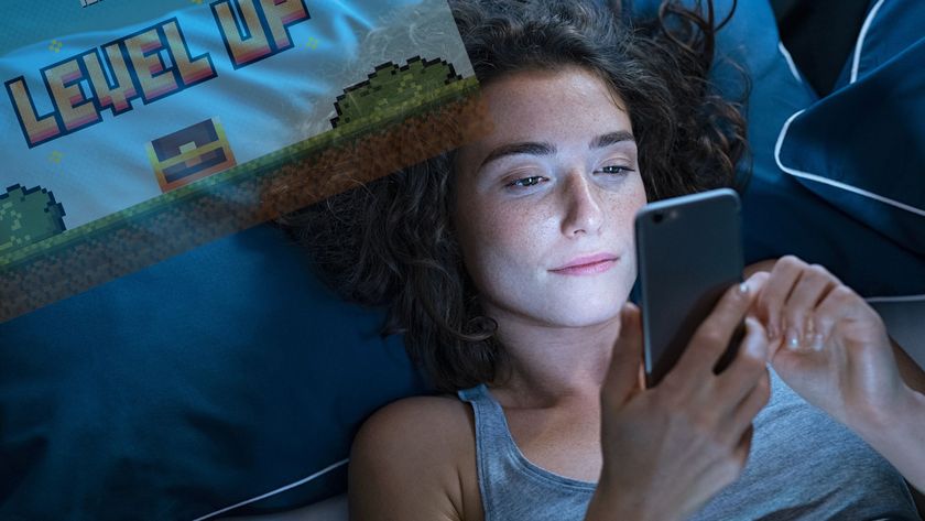 A woman lies in bed in the dark with her phone directed at her face. In the top left corner is a faded screen from a video game