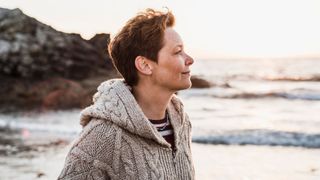 Woman looking out at the sea wearing jumper