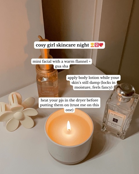 A beside table with a candle, perfume, and a flower hair clip, with information about 'cosy girl skincare' 