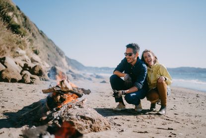 A couple enjoys a campfire on the beach.