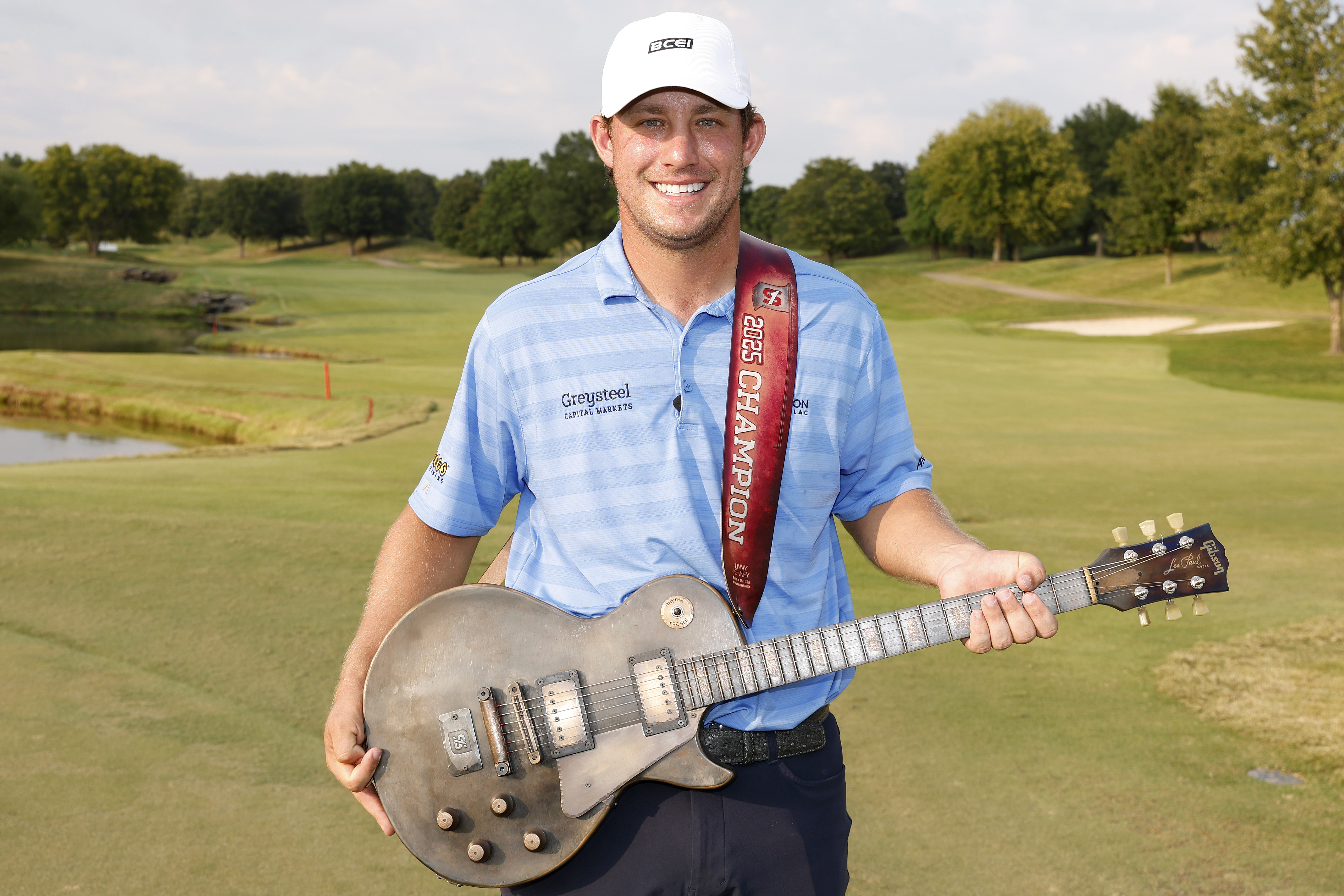 Zach Bauchou holds a guitar trophy after winning on the Korn Ferry Tour