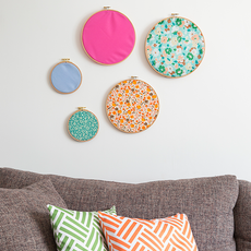wall art with fabric-covered hoops and grey sofa