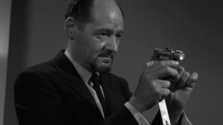 A man holing a gadget in the Twilight Zone episode Valley Of The Shadow