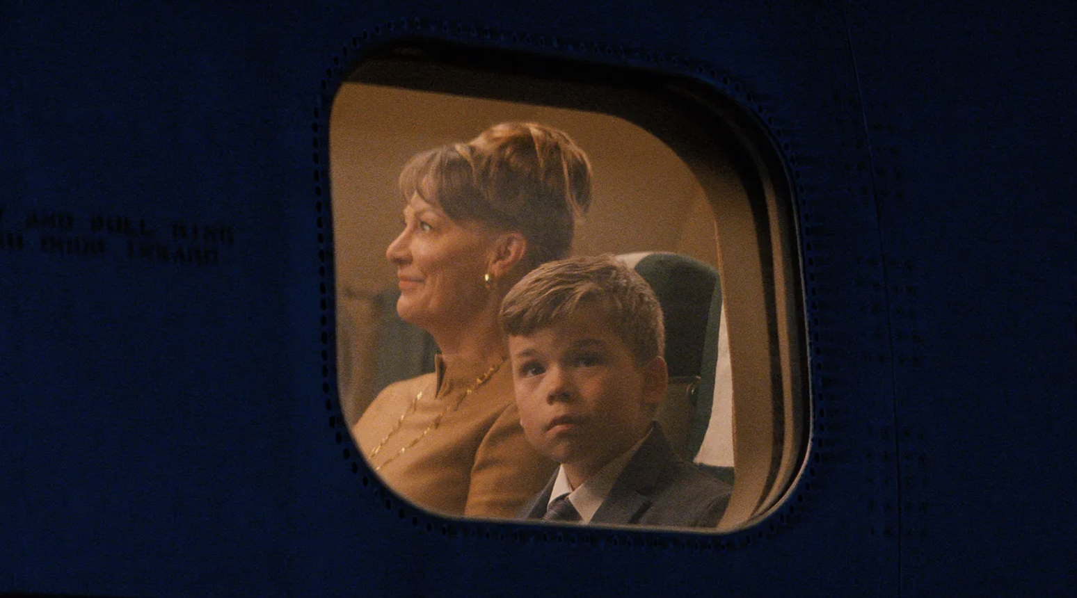 a production image from propeller one-way night coach showing a young boy and his both looking out of a window of a plane