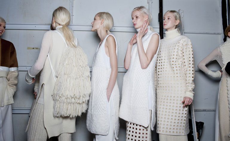 Female models line up for runway in white &amp; cream clothing