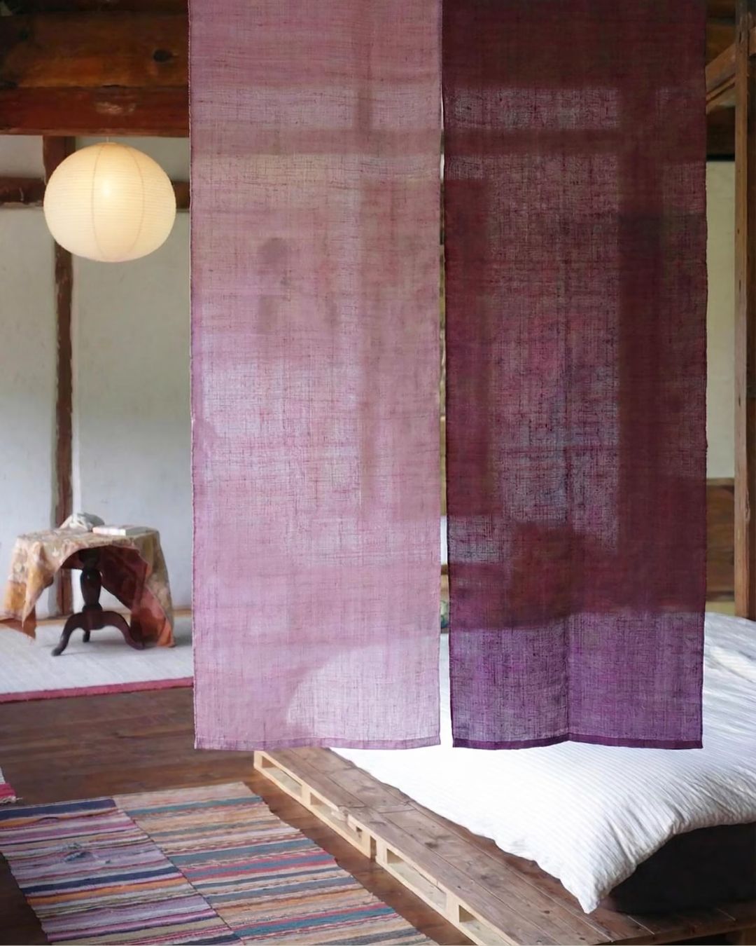 Customize Japanese Noren Curtain in Pink &amp;amp; Purple in a Japanese-style bedroom with wooden floors, striped rugs, and a pendant paper lamp.