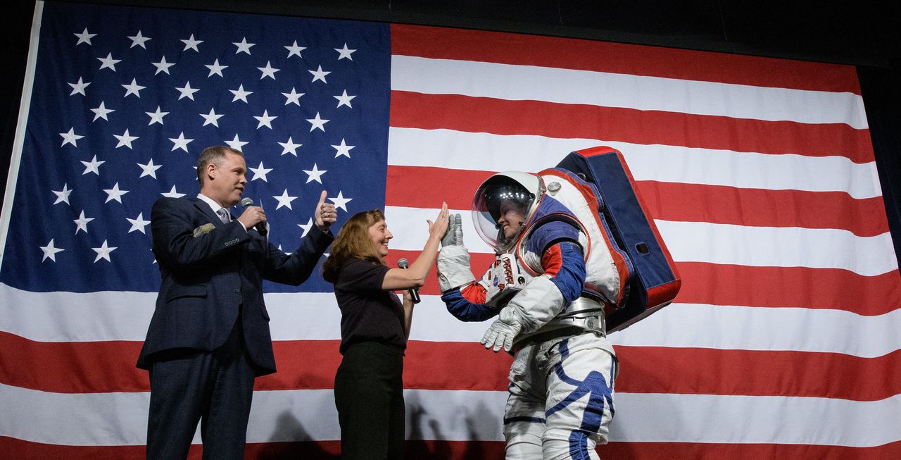 NASA Administrator Jim Bridenstine, left, gives a thumbs up as Amy Ross, a spacesuit engineer at NASA&rsquo;s Johnson Space Center, center, high fives Kristine Davis, a spacesuit engineer at NASA&rsquo;s Johnson Space Center, wearing a ground prototype of NASA&rsquo;s new Exploration Extravehicular Mobility Unit (xEMU), after a demonstration of the suits enhanced mobility, Tuesday, Oct. 15, 2019 at NASA Headquarters in Washington.