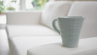 white sofa with a coffee mug on the arm