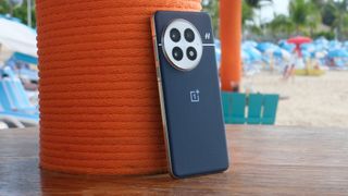 OnePlus 13 phone in blue on a table, propped up against a pole covered in wound orange rope