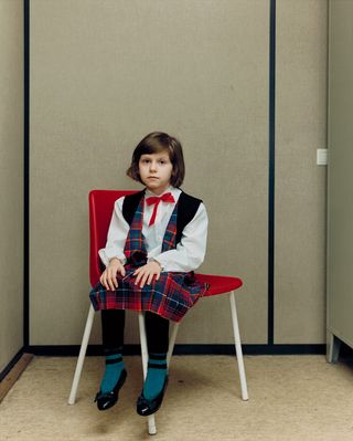 Young child wearing tartan clothing sitting on a chair