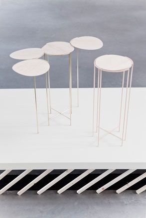 A table constructed from four white circular tops joined to make one piece, and a matching stool beside it