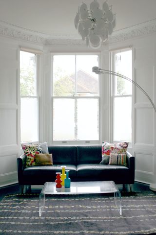 White bay window with frosted film in living room with gray carpet and blue couch